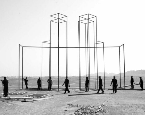 10 people on a flat dirt surface constructing a tall