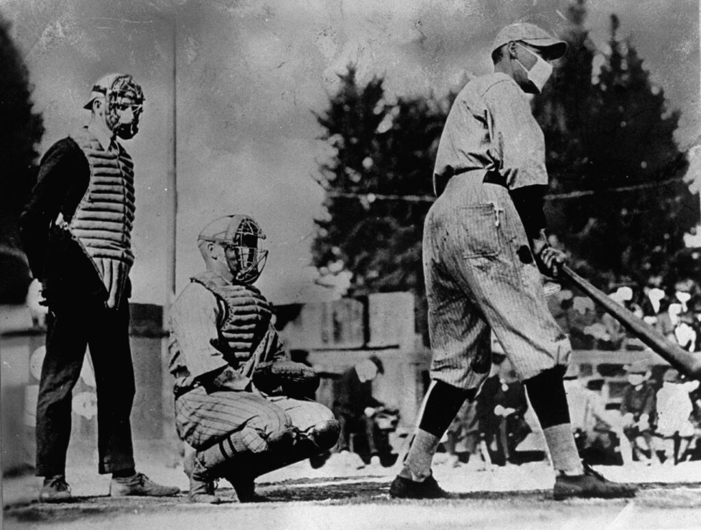 Vintage, black and white photograph of a baseball game showing a batter, catcher, and umpire with a crowd in the background