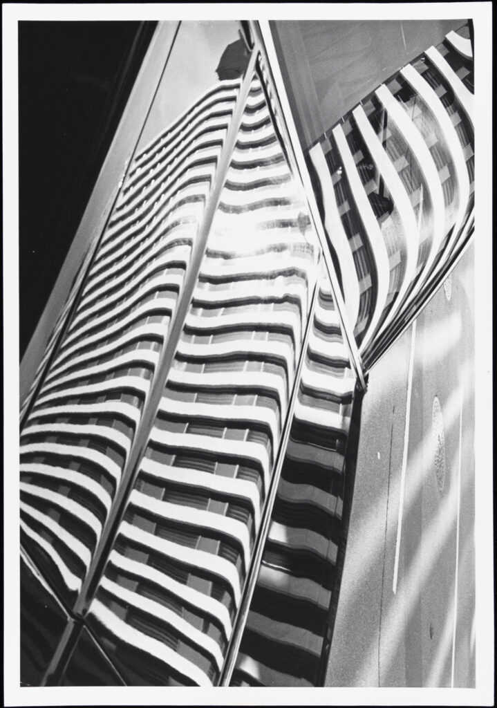 Black and white photograph of the reflection of a building in another building's glass