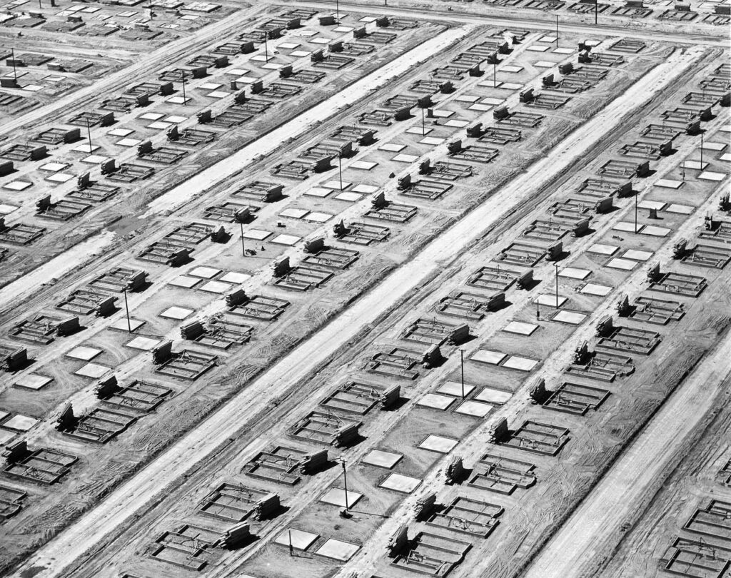 Aerial view of multiple rows of foundations on dirt roads under construction