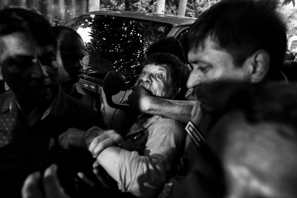 Black and white photograph of a man being gagged by another man's hand in a crowd