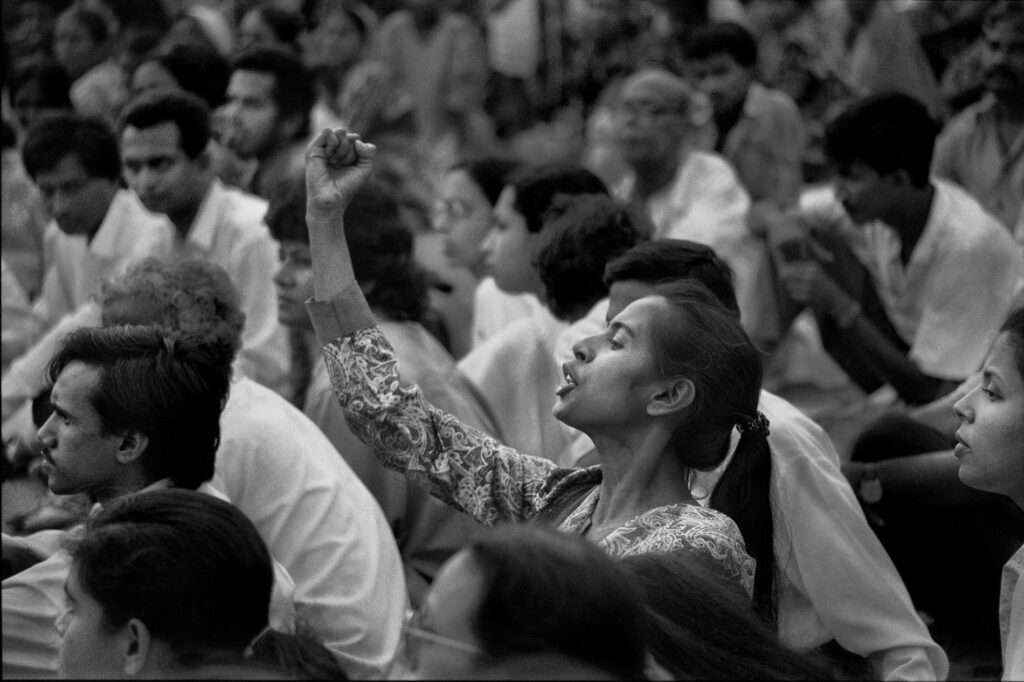 Black and white photograph of a woman raising her fist in a crowd