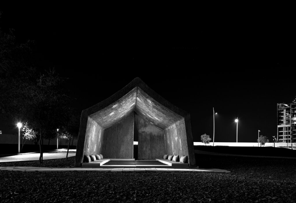 night scene of a concrete tent with pillows inside and street lights around it