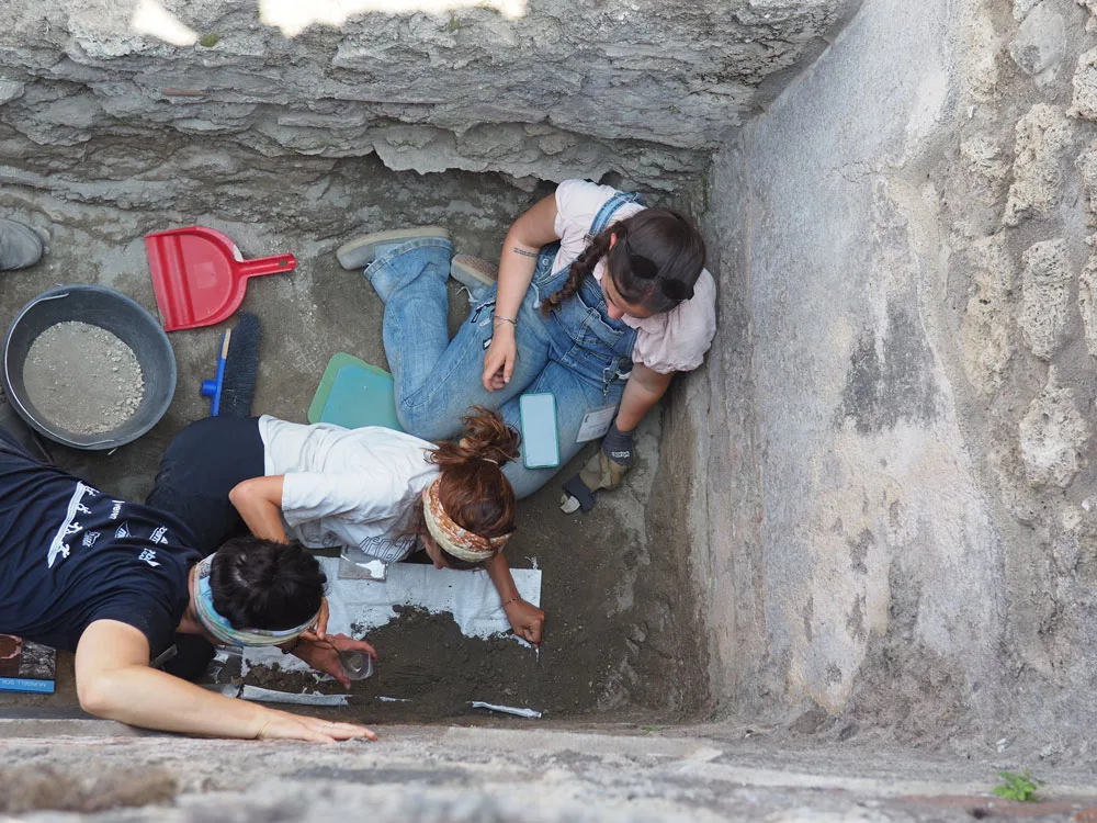 Three people excavating soil in a hole.