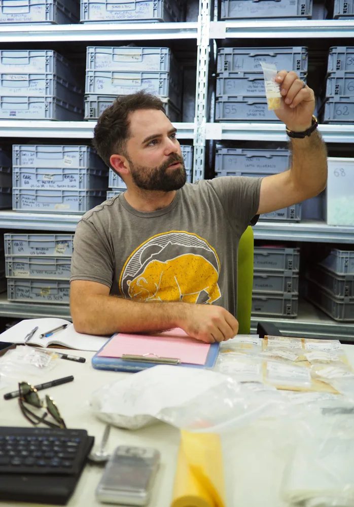 Man looking at sample in small plastic bag.