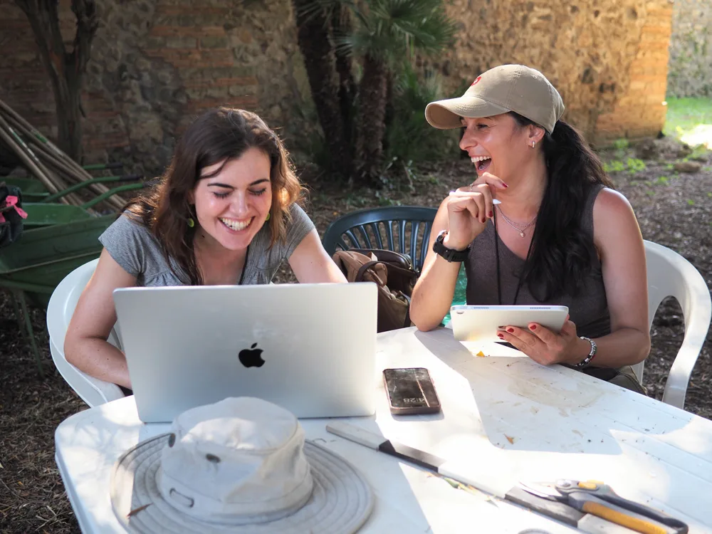 Two women with a computer smiling.