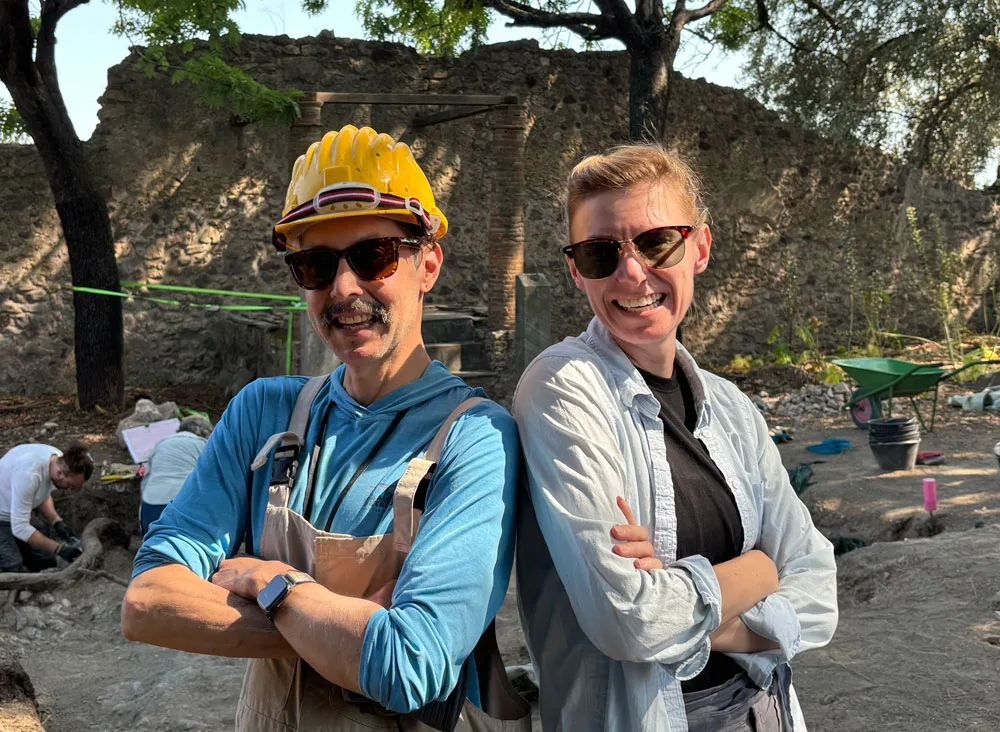 Man and woman standing with folded arms smiling.