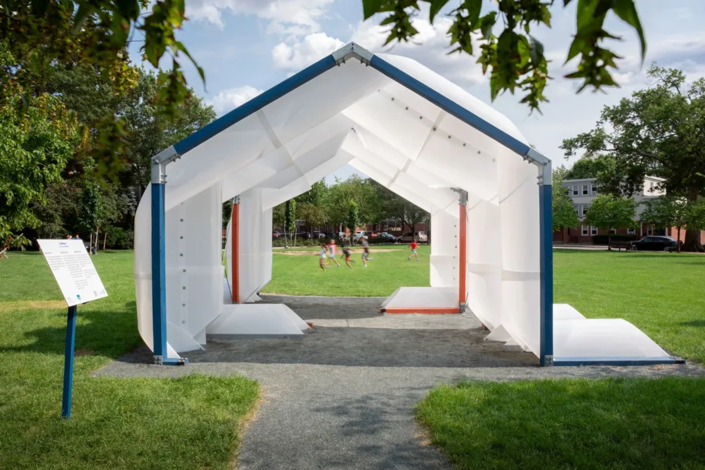 White plastic open-air pavilion surrounded by grass.