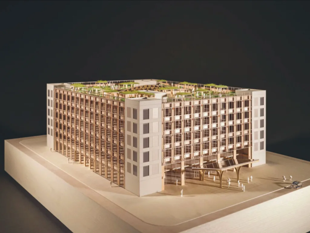 A wooden architectural model of a modern, multi-story building with a spacious rooftop garden and open air first floor, featuring a grid pattern.