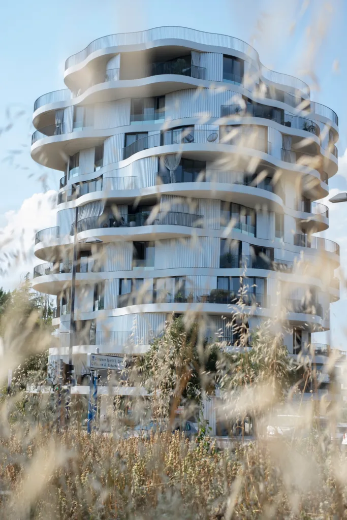 A residential housing tower by Farshid Moussavi Architecture with fields in the foreground.