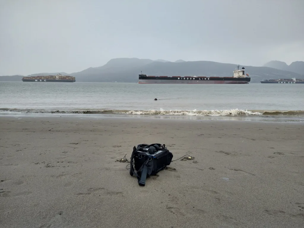 Recording equipment on a beach with large ships in the water in the distance.