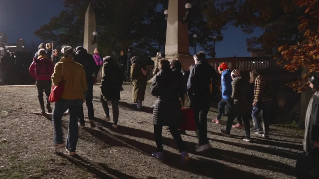 A group of people participate in a soundwalk, crossing a bridge in Cambridge. 