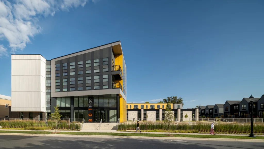 Renovated 1960s building with yellow accents and many windows.