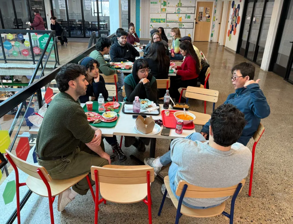People sit at three tables talking and eating a meal.