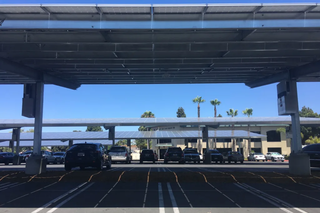 A photograph showing cars parked beneath solar panels. 