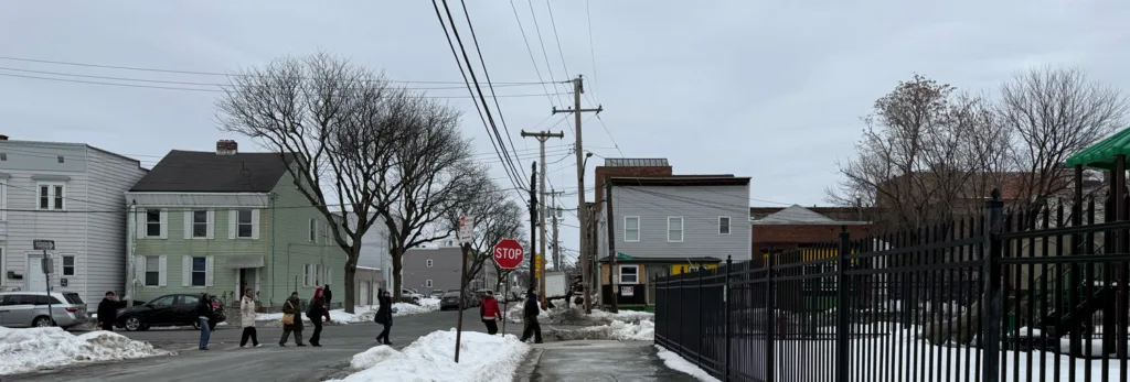 People walking across the street in a residential neighborhood.