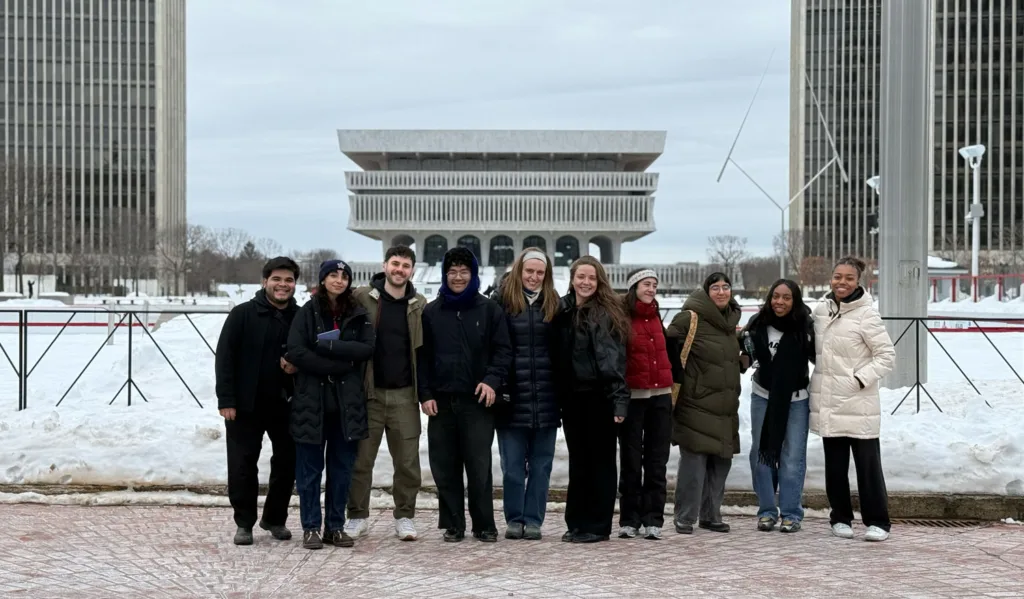 Ten people standing in front of modernist buildings.