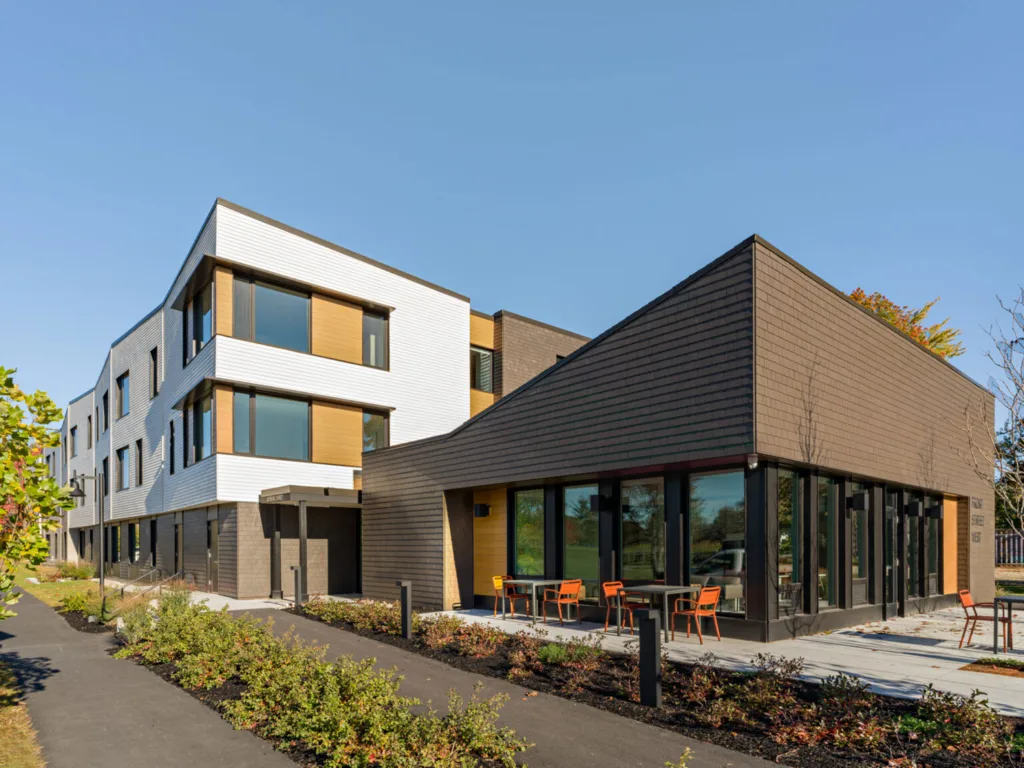 Low-rise housing development with shingled accents, natural wood, and brick.
