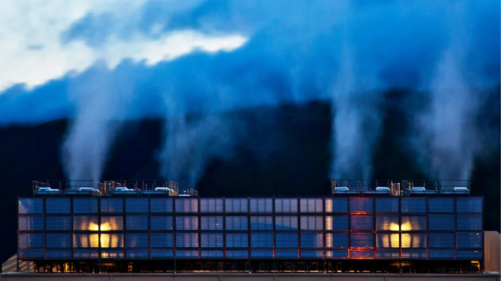 A view of a large data center building spewing steam into the air.