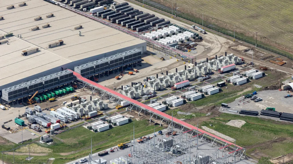 An aerial view of the exterior of a data center showing a large number of generators and other equipment for electrical transmission.