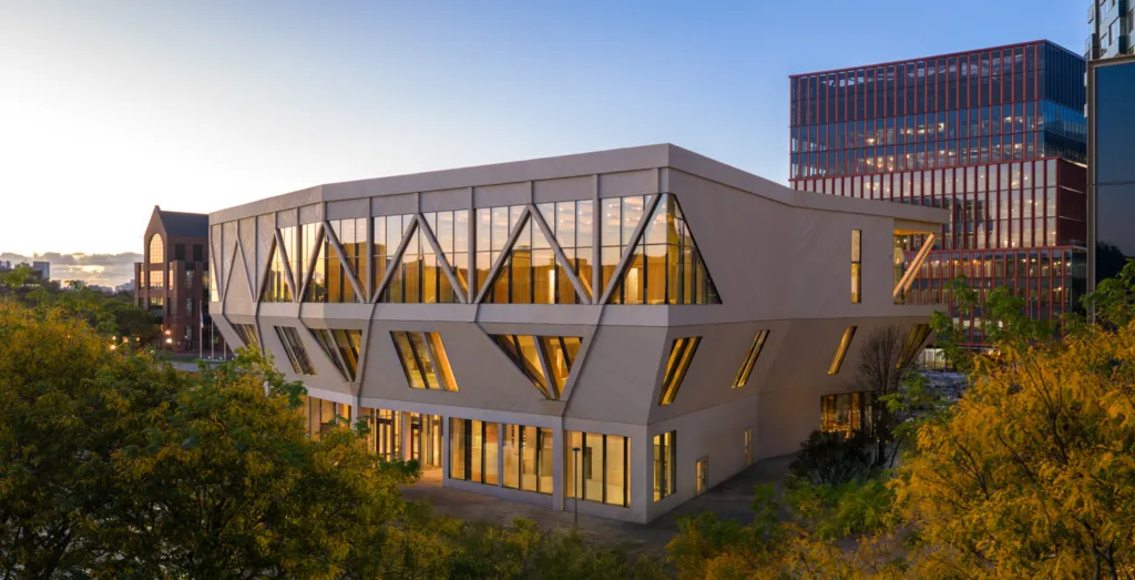 Large, next like building made of mass timber sitting among trees.