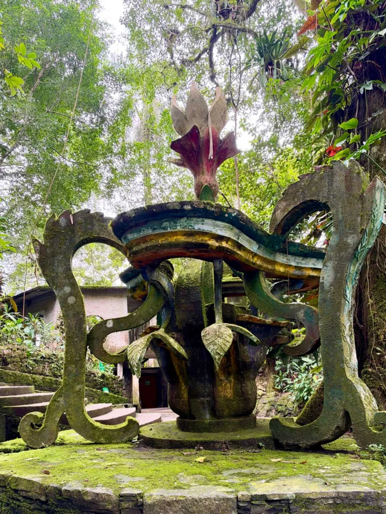 A multicolored concrete folly with moss and vegetation surrounding it.