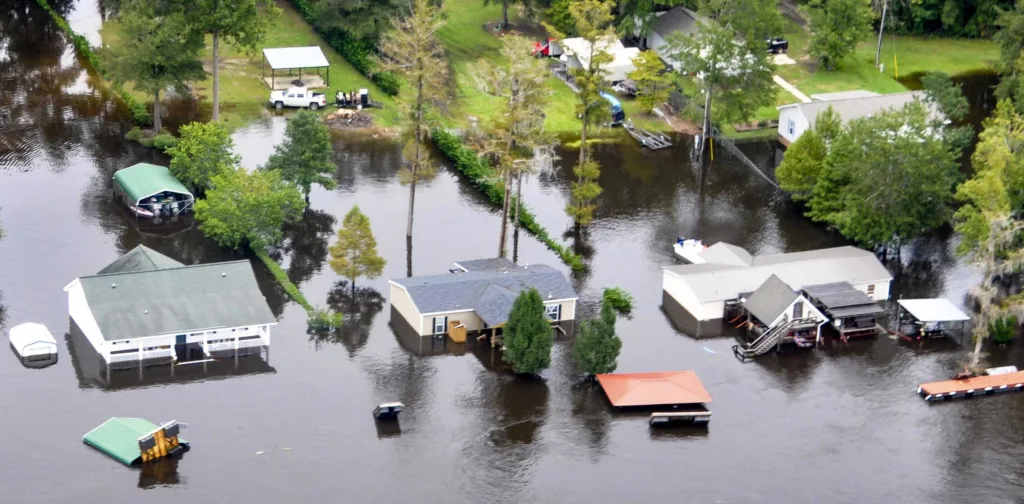 Aerial photo of a flooded neighborhood, wit houses partially subsumed and only a piece of land visible.